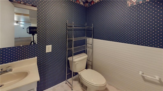 bathroom featuring toilet, vanity, and wallpapered walls