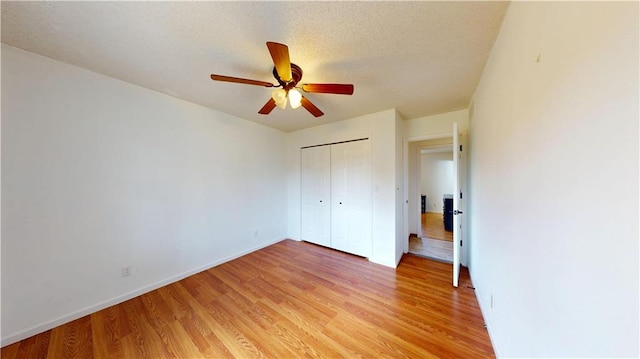 unfurnished bedroom featuring ceiling fan, light wood-type flooring, a closet, and baseboards