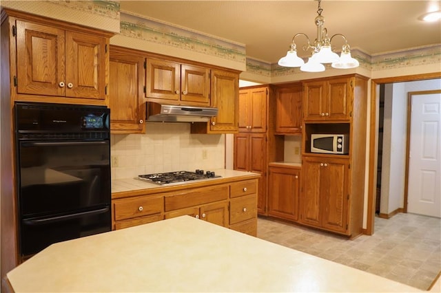 1203 E Quincy St, Pittsburg, KS 66762 - kitchen with dobule oven black, stainless steel gas cooktop, a chandelier, light countertops, and under cabinet range hood