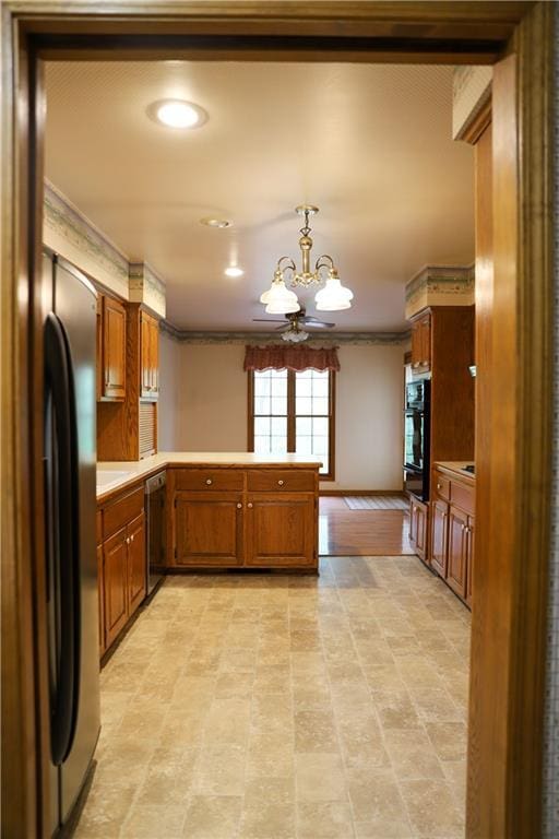 1203 E Quincy St, Pittsburg, KS 66762 - kitchen with a peninsula, a notable chandelier, crown molding, brown cabinetry, and black appliances