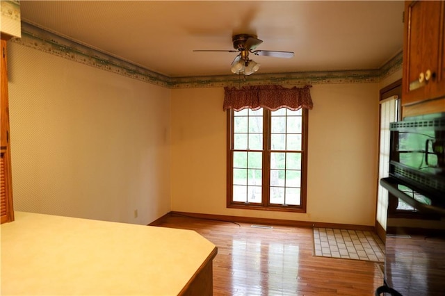 1203 E Quincy St, Pittsburg, KS 66762 - unfurnished dining area with wood finished floors, a ceiling fan, and baseboards
