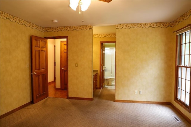 1203 E Quincy St, Pittsburg, KS 66762 - carpeted empty room with a wealth of natural light, a ceiling fan, visible vents, and baseboards