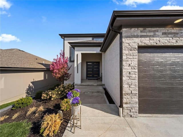 entrance to property featuring an attached garage, stucco siding, driveway, and stone siding