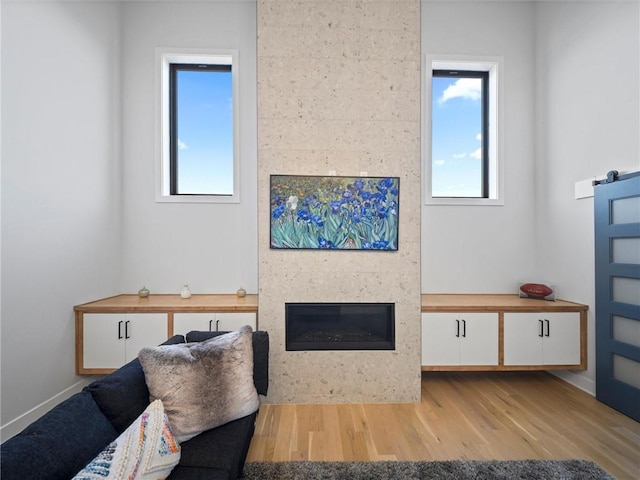 living room with baseboards, a fireplace, wood finished floors, and a wealth of natural light