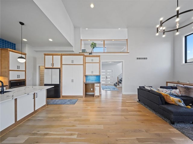 living room with an inviting chandelier, stairs, recessed lighting, light wood-type flooring, and visible vents