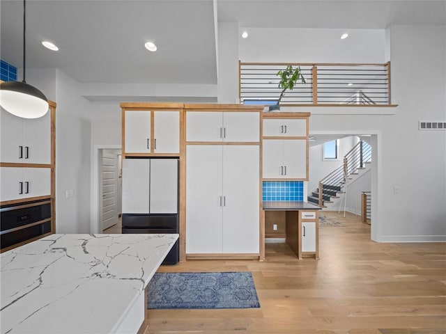 kitchen featuring white cabinetry, visible vents, light wood-style flooring, and oven