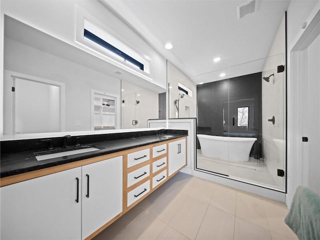 bathroom with double vanity, visible vents, a shower stall, a sink, and a soaking tub