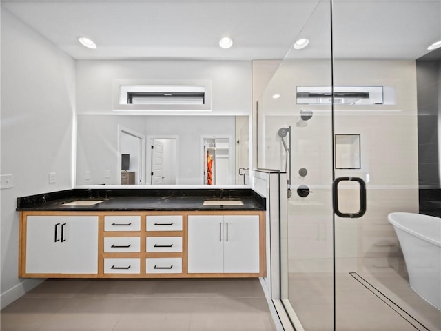 bathroom featuring double vanity, a sink, a soaking tub, and a stall shower