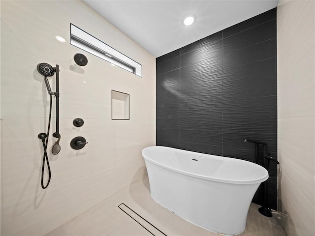 bathroom with tile walls, tiled shower, and a freestanding bath