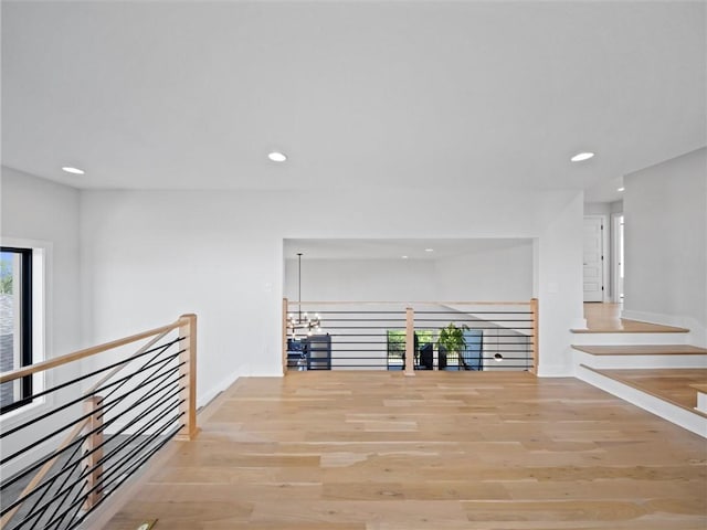 hallway featuring recessed lighting, an upstairs landing, a healthy amount of sunlight, and light wood-type flooring