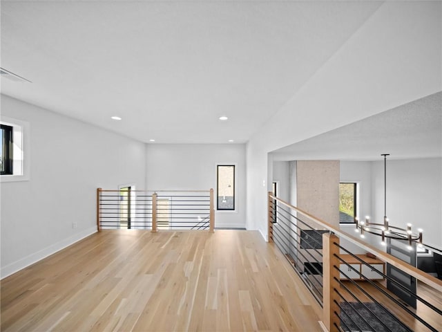 interior space featuring an inviting chandelier, baseboards, light wood finished floors, and a wealth of natural light