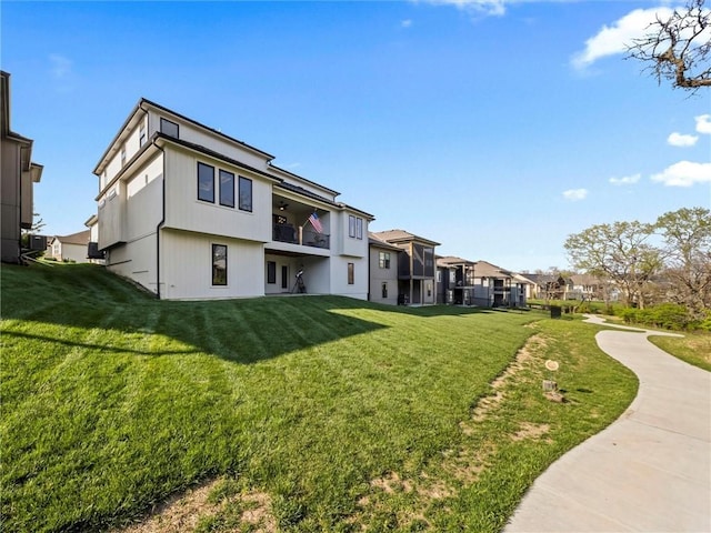 rear view of property with a residential view, a yard, and a balcony