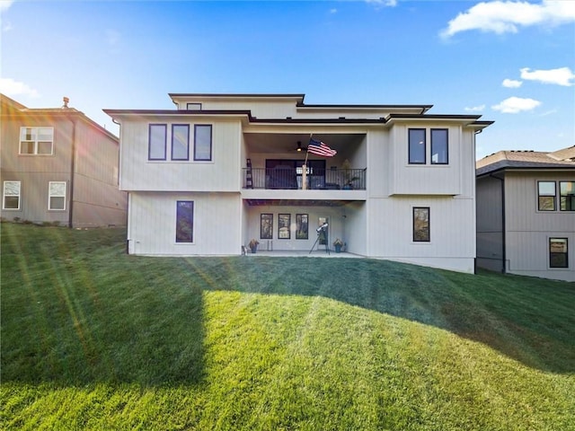 rear view of house with a yard, ceiling fan, a balcony, and a patio area