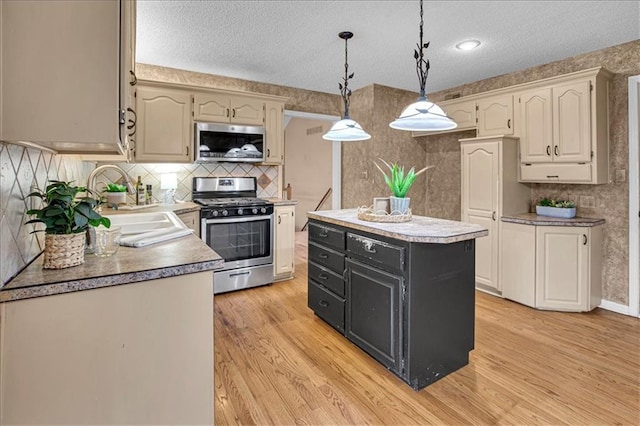 120 NW Whitlock Dr, Lees Summit, MO 64081 - kitchen with stainless steel appliances, light wood-style flooring, a textured ceiling, hanging light fixtures, and a kitchen island