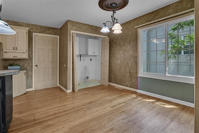 120 NW Whitlock Dr, Lees Summit, MO 64081 - unfurnished dining area featuring light wood-type flooring, baseboards, a chandelier, and a textured ceiling