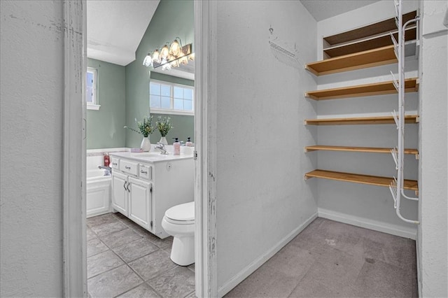 120 NW Whitlock Dr, Lees Summit, MO 64081 - bathroom featuring toilet, vanity, a garden tub, a textured wall, and baseboards