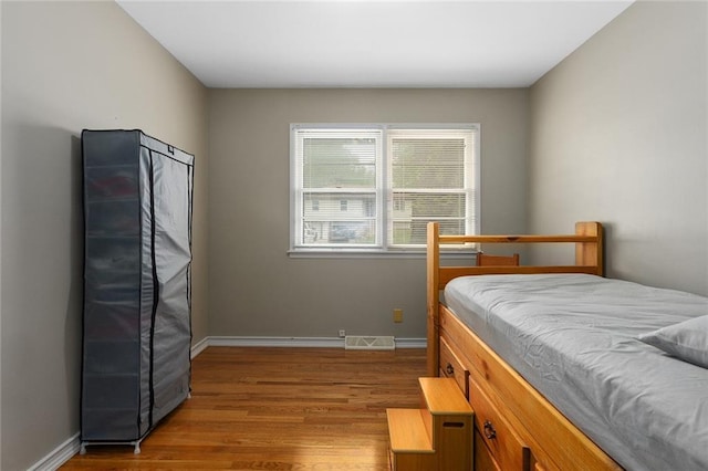 bedroom with visible vents, wood finished floors, and baseboards