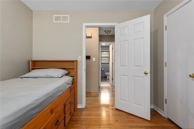 bedroom with light wood-type flooring, baseboards, and visible vents