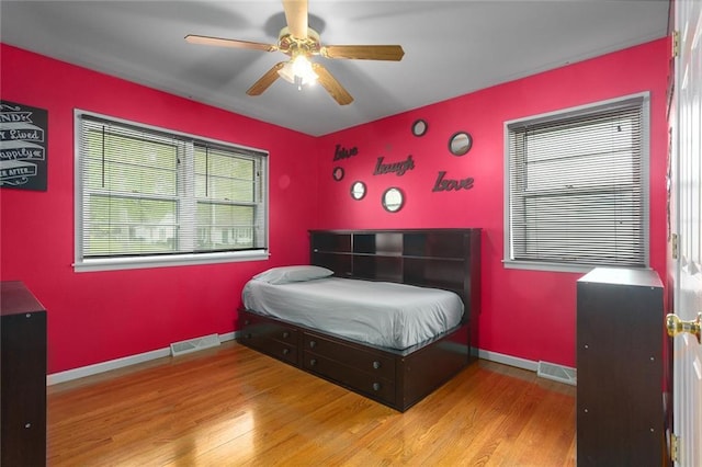 bedroom with visible vents, baseboards, wood finished floors, and ceiling fan