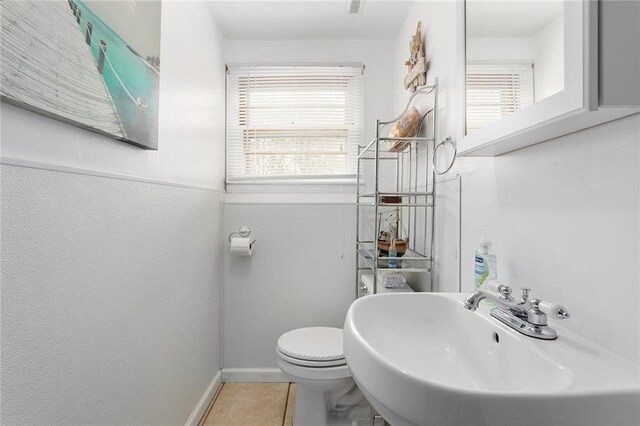 bathroom with tile patterned flooring, baseboards, a sink, and toilet