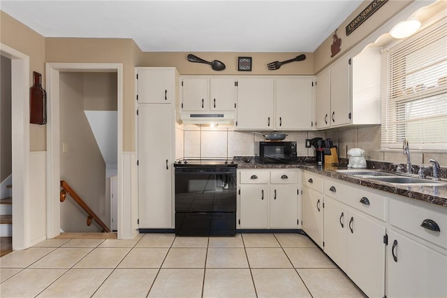 kitchen with a sink, light tile patterned flooring, white cabinetry, under cabinet range hood, and black appliances