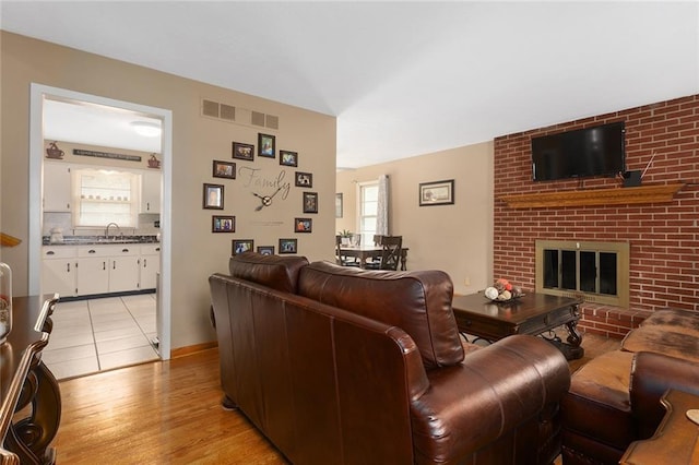 living area featuring visible vents, light wood-style flooring, and a fireplace