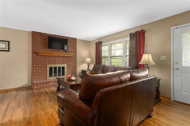 living area with a brick fireplace, wood finished floors, and baseboards