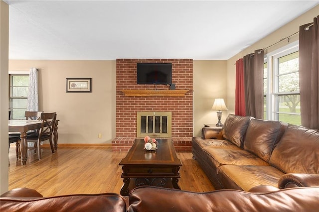 living room featuring a fireplace, a wealth of natural light, wood finished floors, and baseboards