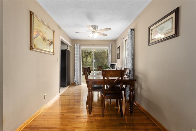 dining room featuring a ceiling fan, light wood-style flooring, and baseboards