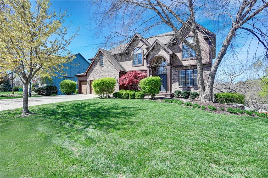 7800 Alden Rd, Lenexa, KS 66216 - traditional home with an attached garage, concrete driveway, a front lawn, and brick siding