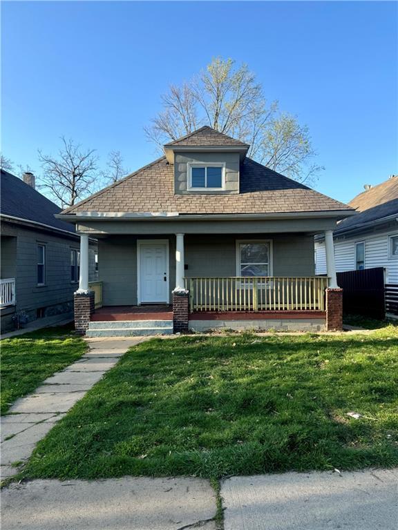 bungalow featuring a front yard, covered porch, and roof with shingles
