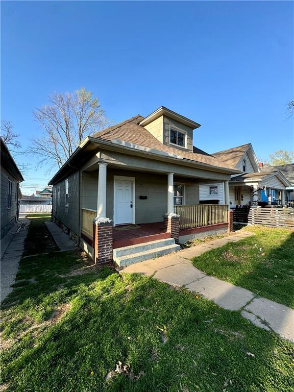 bungalow-style house featuring roof with shingles, a porch, fence, and a front lawn
