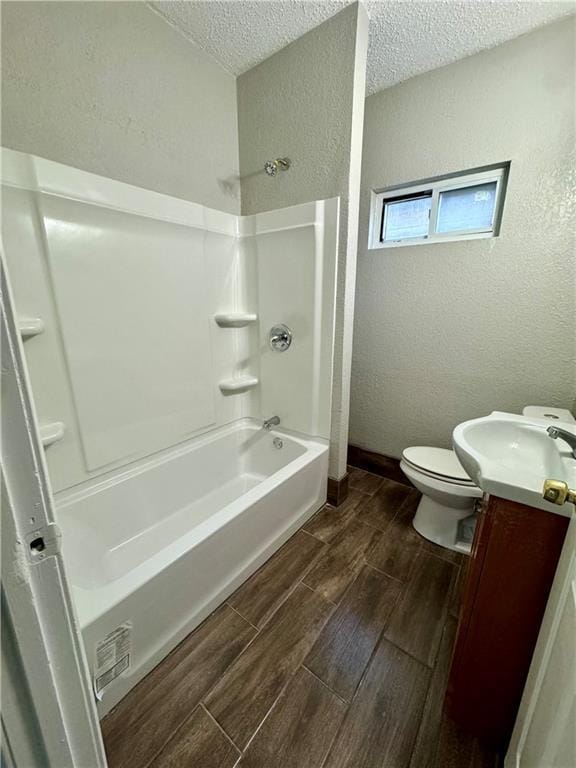 full bath with toilet, a textured ceiling, a textured wall, and wood finish floors