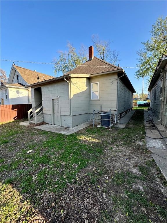 back of property featuring central air condition unit, fence, and a chimney