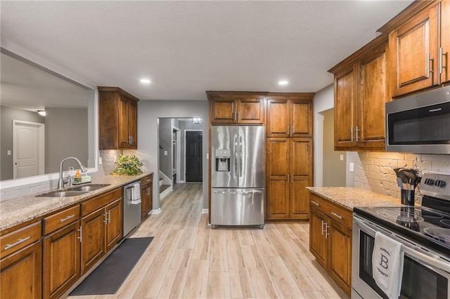 6806 N Euclid Ave, Kansas City, MO 64119 - kitchen with light stone counters, a sink, light wood-style flooring, stainless steel appliances, and decorative backsplash