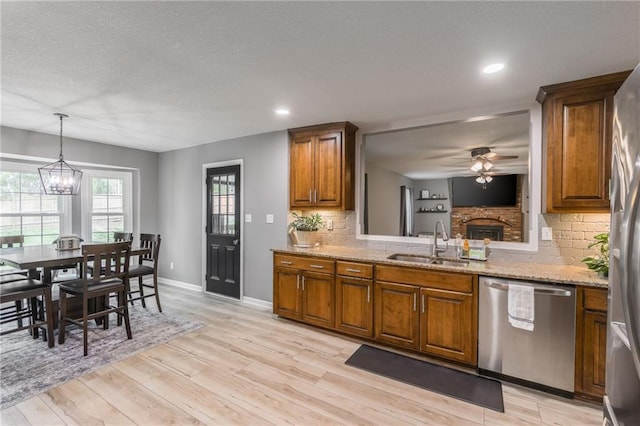 6806 N Euclid Ave, Kansas City, MO 64119 - kitchen with brown cabinetry, appliances with stainless steel finishes, a fireplace, a sink, and ceiling fan with notable chandelier