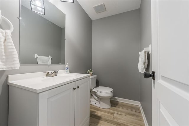 6806 N Euclid Ave, Kansas City, MO 64119 - bathroom featuring visible vents, wood finished floors, vanity, baseboards, and toilet