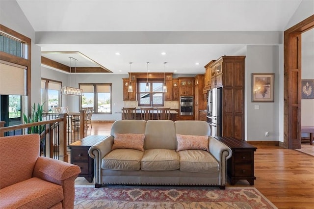living area with light wood-style floors, baseboards, recessed lighting, and lofted ceiling
