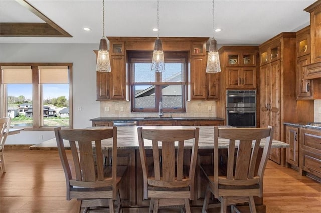 kitchen with appliances with stainless steel finishes, brown cabinets, a sink, backsplash, and recessed lighting