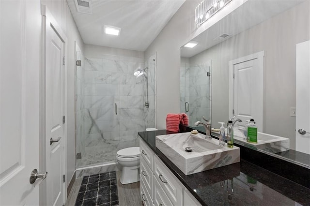 bathroom featuring toilet, vanity, and a shower stall