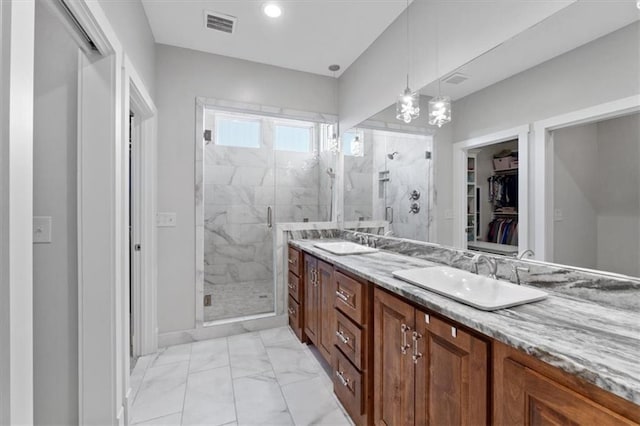 bathroom with marble finish floors, a shower stall, double vanity, and a walk in closet