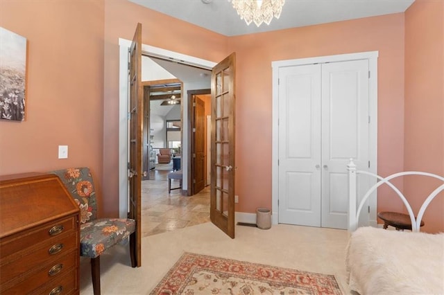 bedroom featuring light carpet, a closet, french doors, baseboards, and a chandelier