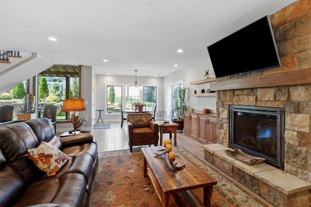 living area with a fireplace, recessed lighting, a chandelier, light wood-style flooring, and baseboards
