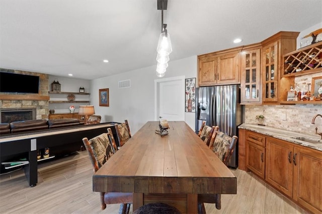 dining space featuring light wood-style flooring, recessed lighting, and a stone fireplace