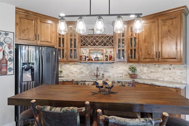 kitchen featuring brown cabinets, backsplash, glass insert cabinets, decorative light fixtures, and recessed lighting