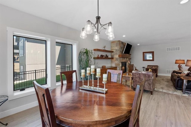 dining area featuring light wood finished floors, baseboards, a fireplace, a chandelier, and recessed lighting