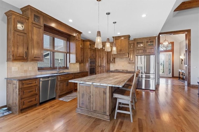 8856 Freedom St, Lenexa, KS 66227 - kitchen featuring appliances with stainless steel finishes, a sink, a chandelier, brown cabinets, and a center island