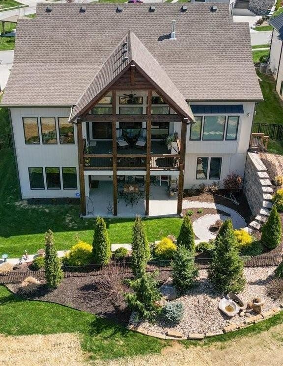 8856 Freedom St, Lenexa, KS 66227 - back of house featuring roof with shingles, a patio area, and a lawn