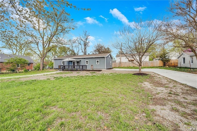 view of front facade featuring driveway, fence, and a front lawn