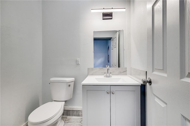 bathroom with toilet, vanity, and baseboards